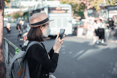 Woman wearing flu mask using phone at road