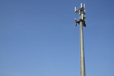 Low angle view of communications tower against clear blue sky