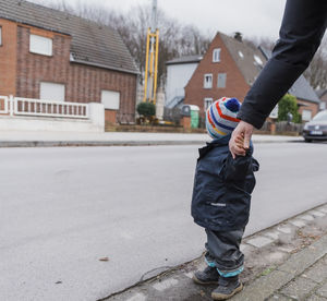 Cropped image of parent and daughter holding hands in city