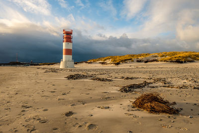 Lighthouse on beach against sky