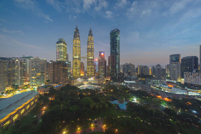 Illuminated buildings in city against sky