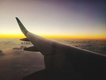 Airplane wing against sky during sunset