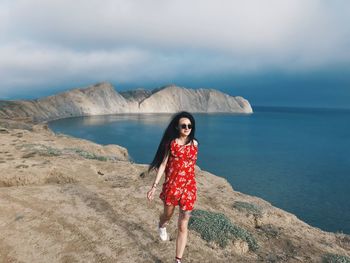 Portrait of young woman at beach against sky