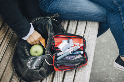 Woman with open bag sitting on bench