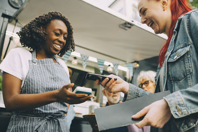 Low angle view of customer paying through smart phone in city