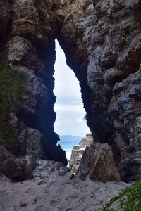 Rock formation by sea against sky