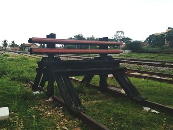 Bench on field in park against clear sky