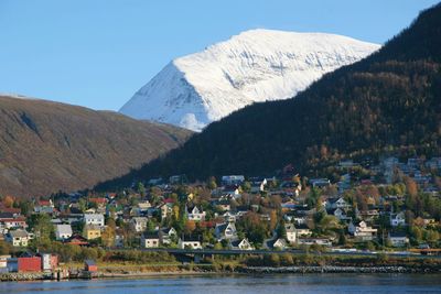 Houses by river and mountains against clear sky