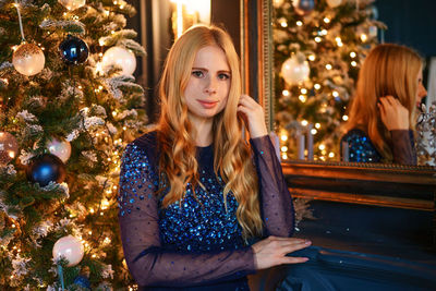 Portrait of woman standing by christmas tree