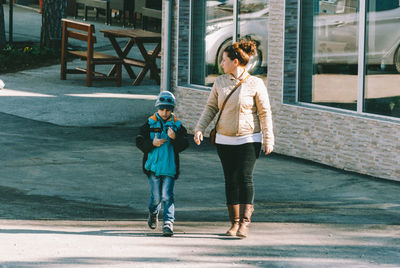 Full length of woman with son walking on road