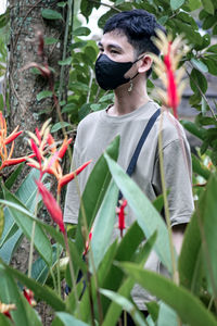 Portrait of young woman standing against plants