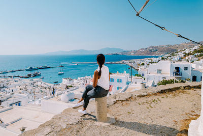 Rear view of woman standing by sea against sky