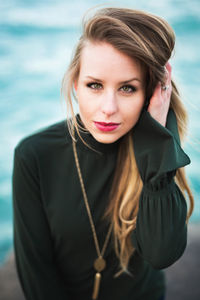 Portrait of beautiful young woman standing against sea