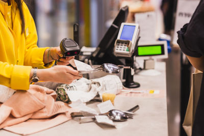 Woman cashier scanning product at checkout counter in store.