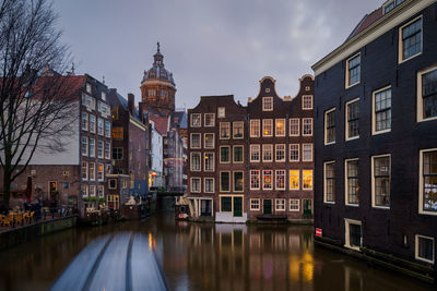 Canal amidst buildings against sky in city