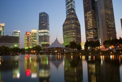 Reflection of illuminated buildings in city against sky