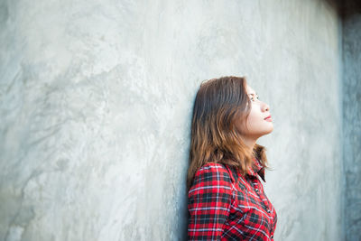 Thoughtful young woman leaning on wall