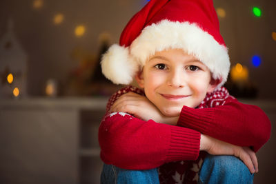 Portrait of smiling boy wearing santa hat sitting at home