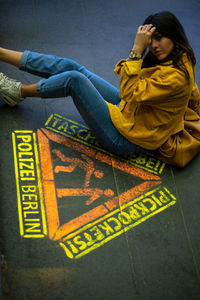 High angle view of man sitting on yellow sign