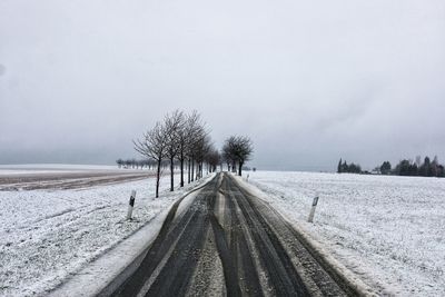 Tire tracks on snow field against clear sky