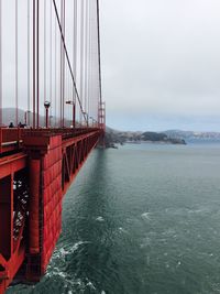 Suspension bridge over sea against sky