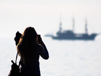 Rear view of woman photographing against sky