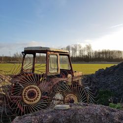 Abandoned tractor by farm against sky