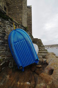 Blue deck chairs on beach against sky