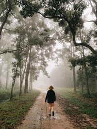 Rear view of man walking on footpath in forest