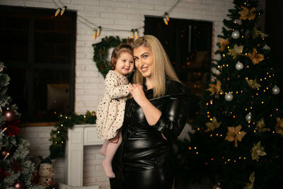 Portrait of a smiling mother and daughter with christmas tree