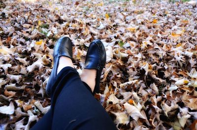 Low section of woman sitting on autumn leaves