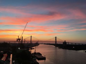 Silhouette bridge over sea against sky during sunset