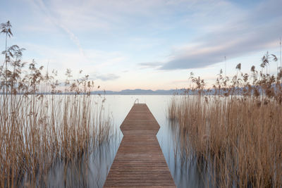 Wooden pier on lake against sky