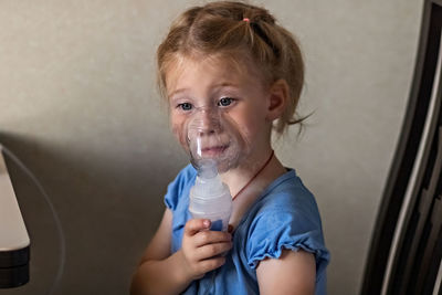 Portrait of cute girl holding camera at home