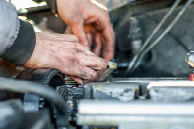 Cropped hand of mechanic working on engine of car