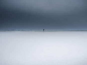 Person on snow covered land against sky