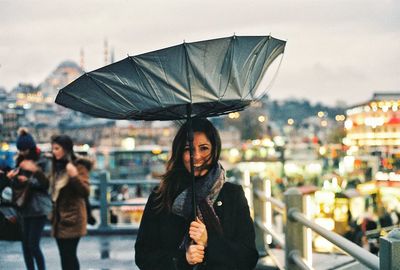 Portrait of woman standing against illuminated city at night