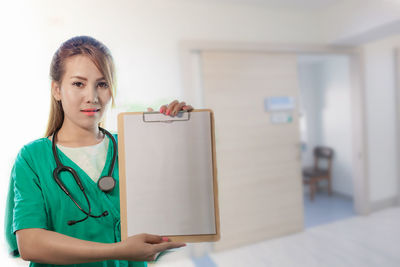 Portrait of young female doctor showing clipboard