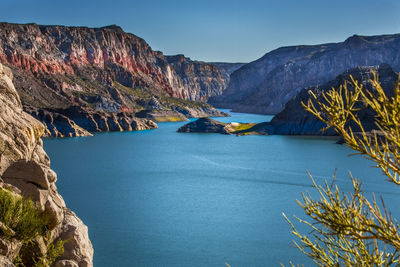 Scenic view of lake and mountains against clear blue sky