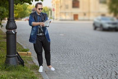 Full length of man holding shoe while standing outdoors