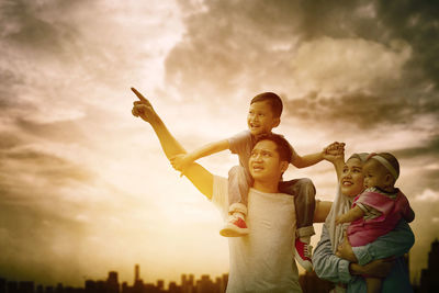 Father with son against sky during sunset