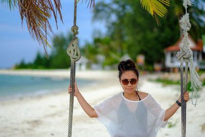 Young woman wearing sunglasses standing against trees