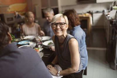 Portrait of cheerful mature woman sitting with friends at table