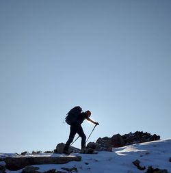 Man standing on snow covered mountain against clear sky