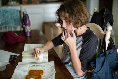 Teen girl licks her fingers after taking a bite of a greasy hash brown