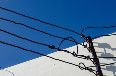 Low angle view of cables against clear blue sky