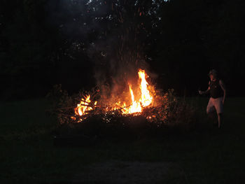 Man standing at bonfire during night