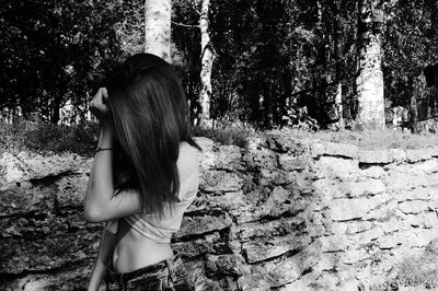 Side view of woman standing by tree in forest