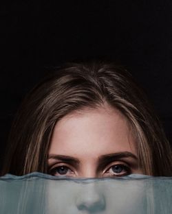 Close-up portrait of beautiful woman against black background