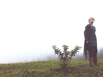Young man standing on field against clear sky